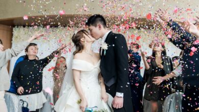 man in black suit kissing woman in white wedding dress