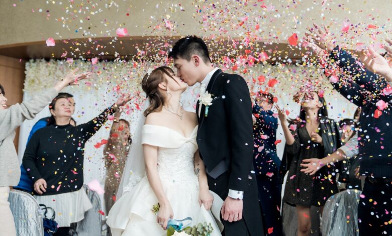 man in black suit kissing woman in white wedding dress