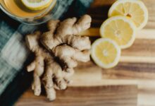 a glass of orange juice next to sliced lemons and ginger