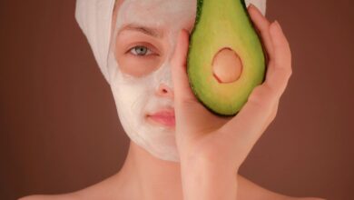 woman with white face mask holding green fruit